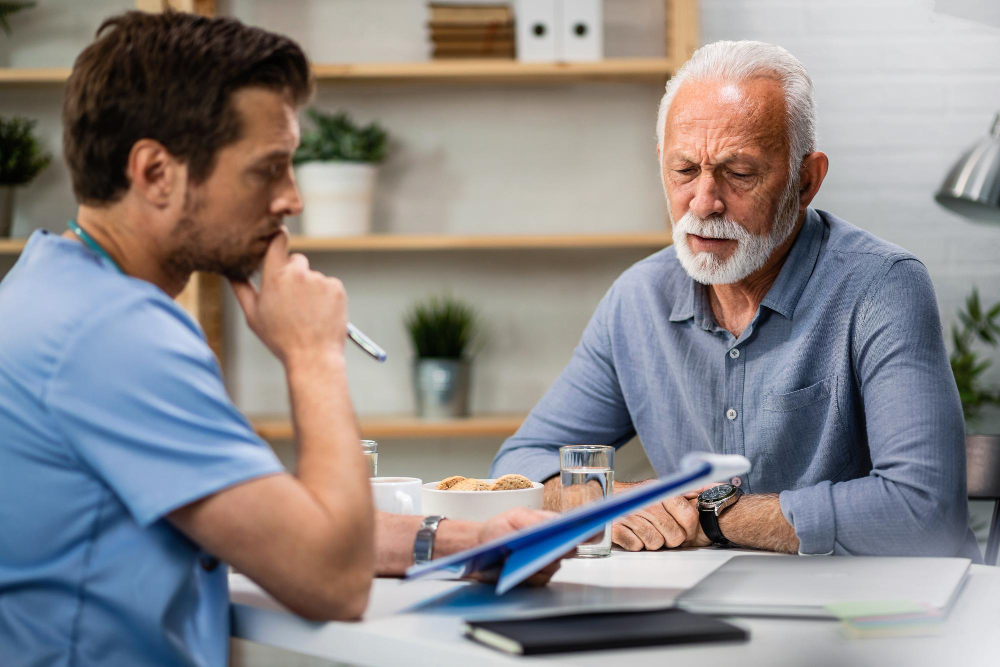 Caregiver reading medical charts to elderly man
