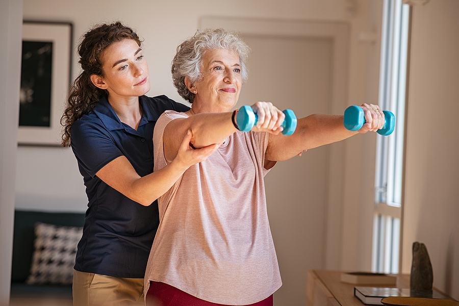 Caregiver helping elderly woman exercise