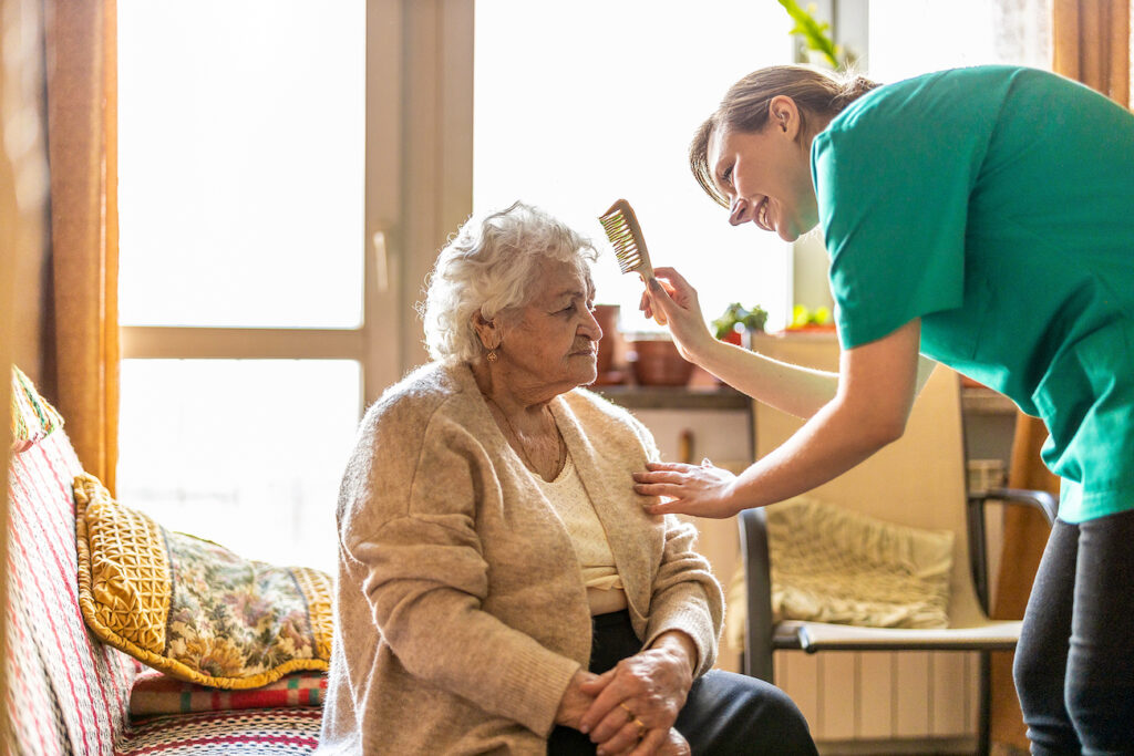 Caregiver brushing elderly woman's hair